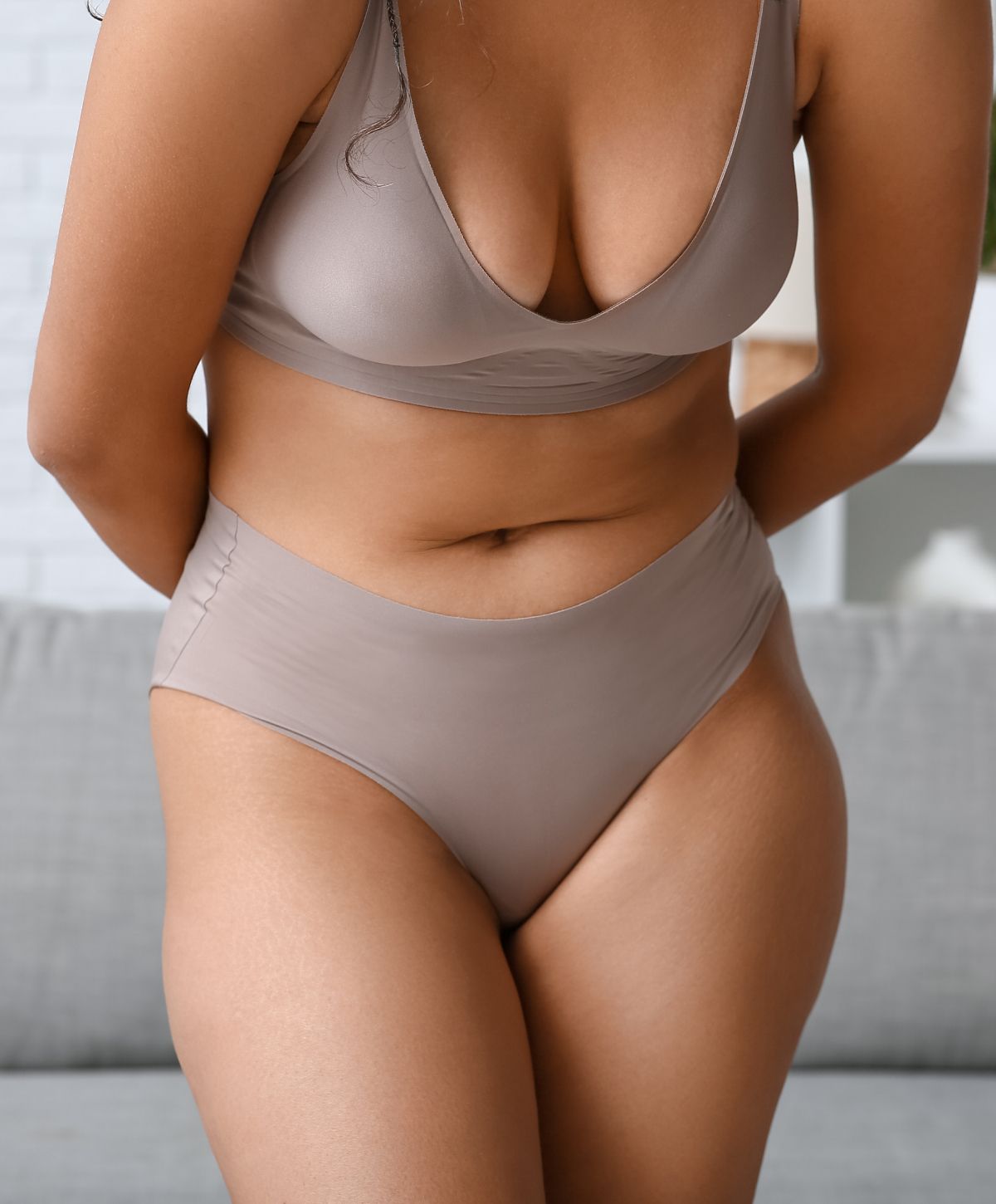 Woman in neutral lingerie posing indoors.